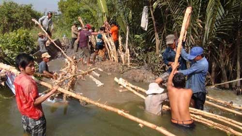 Đến 11g ngày 15/12, nhiều nhà dân, xưởng sản xuất vẫn chìm trong nước. Ảnh: Hàng trăm người gồm lực lượng dân quân tự vệ, đơn vị gia cố cùng đắp đê bao